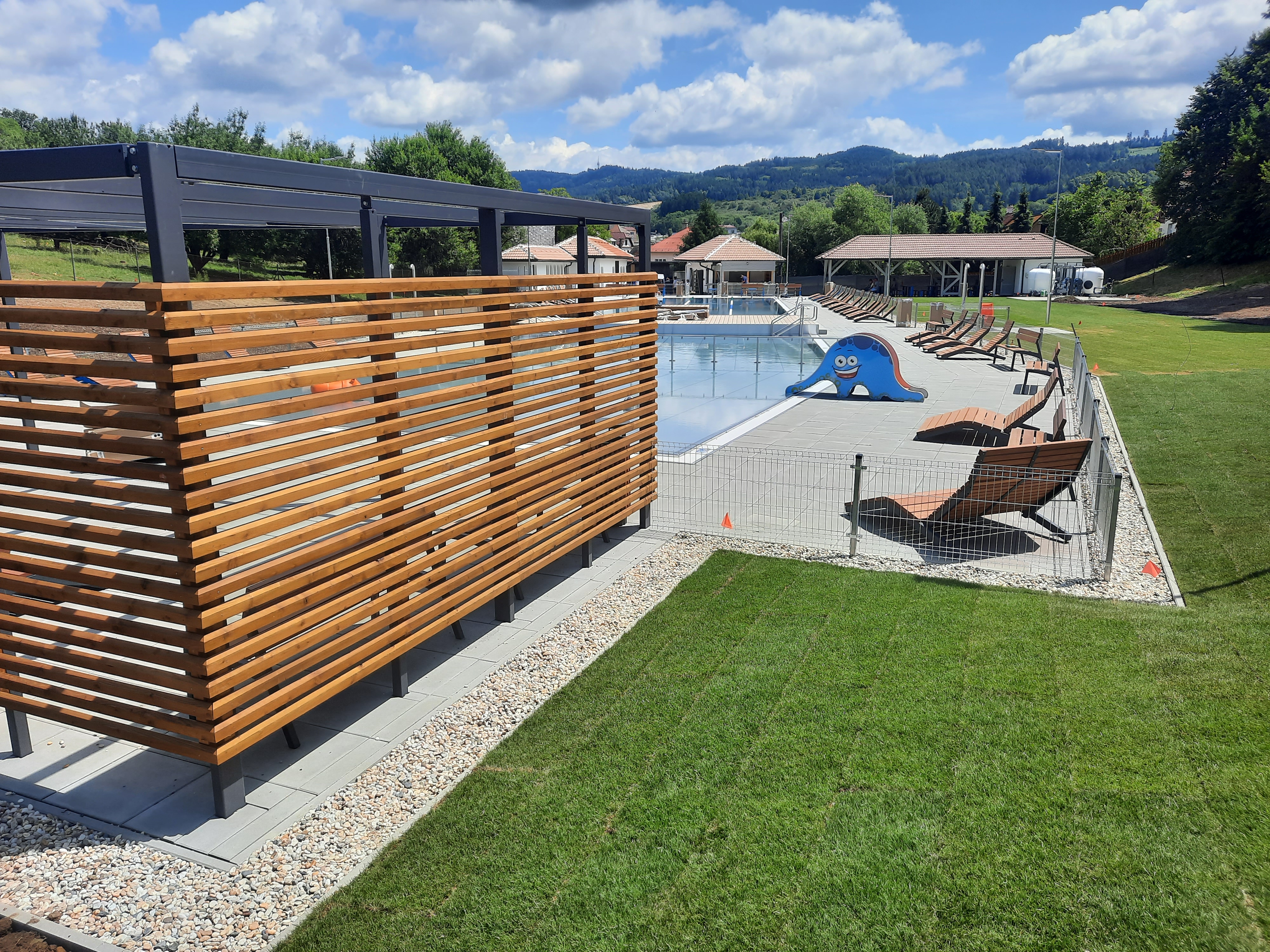 Areál koupaliště s pergolou a dřevěnými lamelami