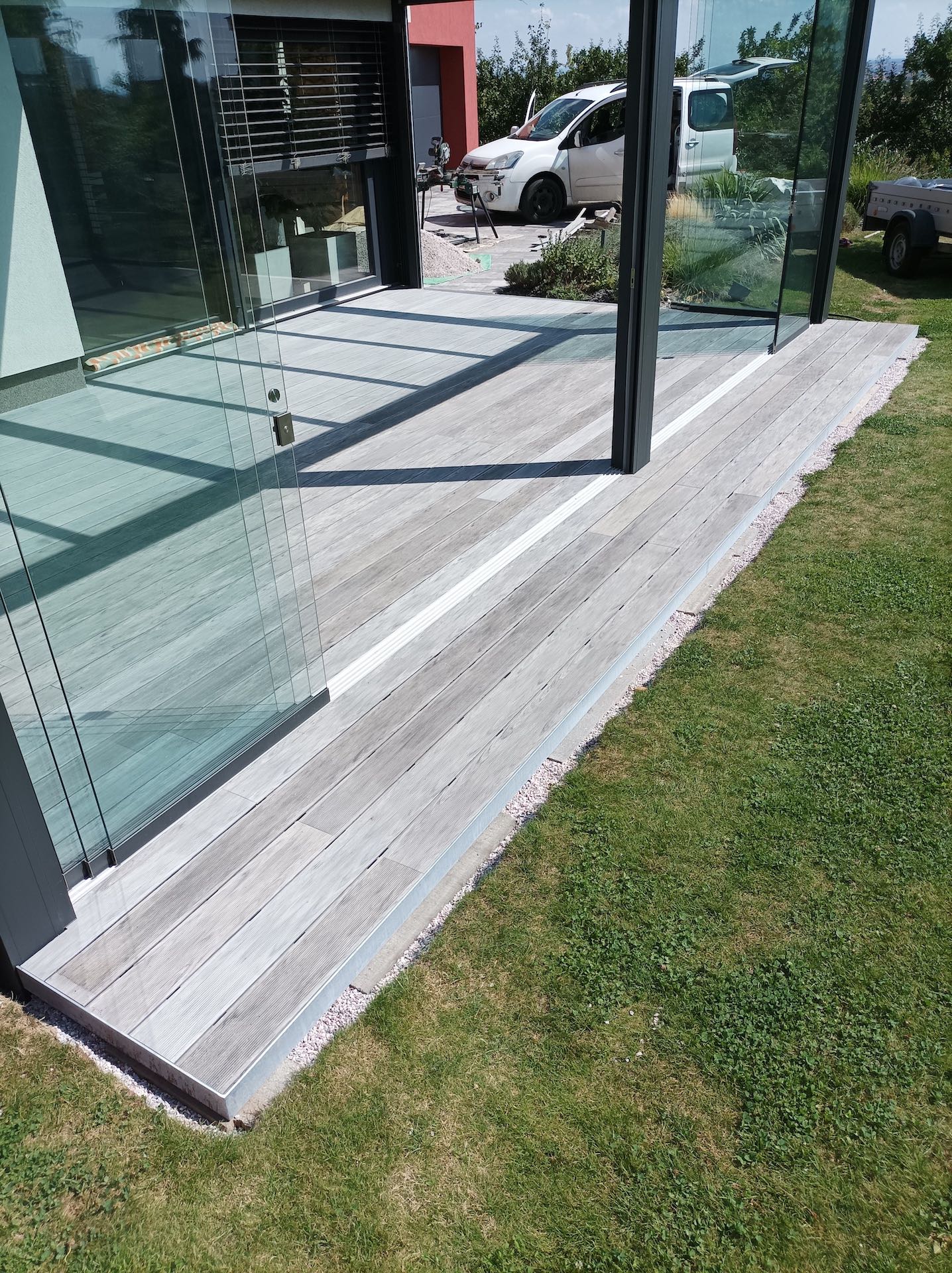 Terasová dlažba u prosklené fasády moderního domu